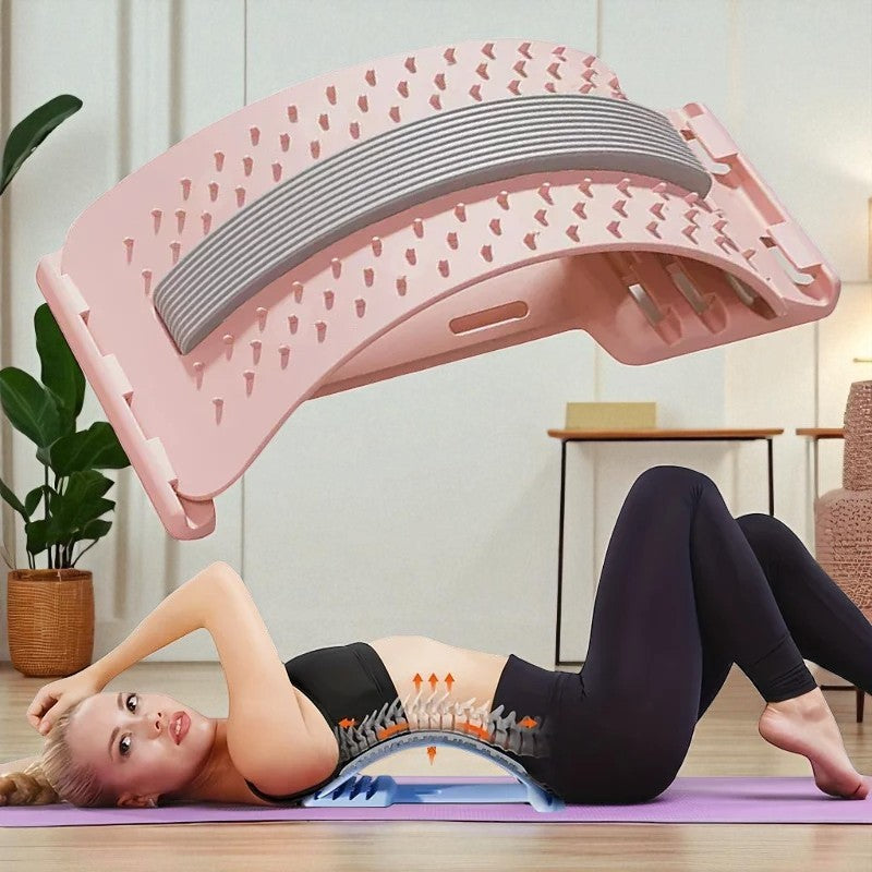 Woman using a pink back stretcher on a mat in a room with a plant and table.