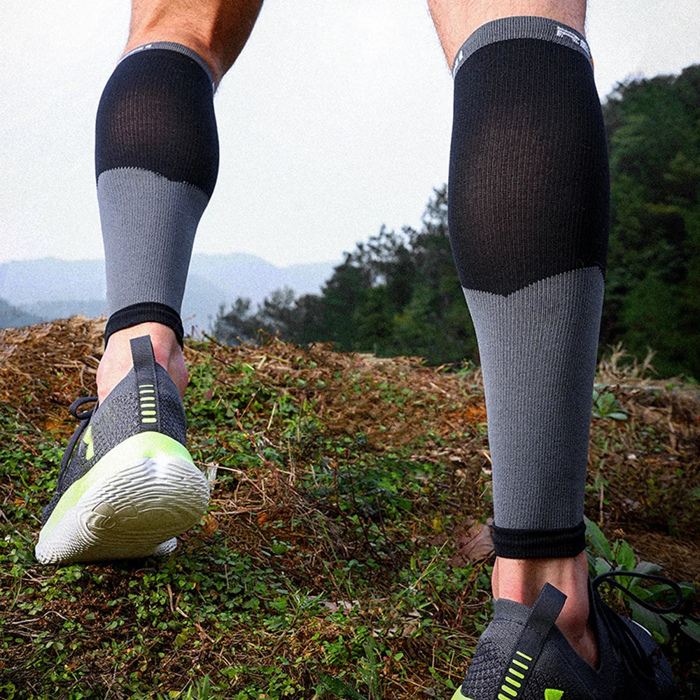 Person wearing black and gray compression sleeves on legs outdoors