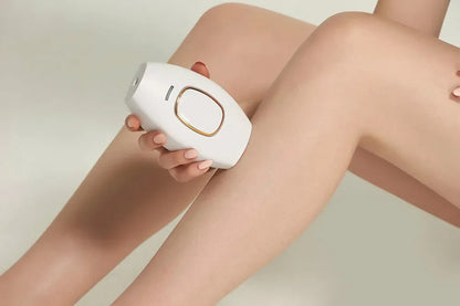 Person using a white hair removal device on their leg against a neutral background
