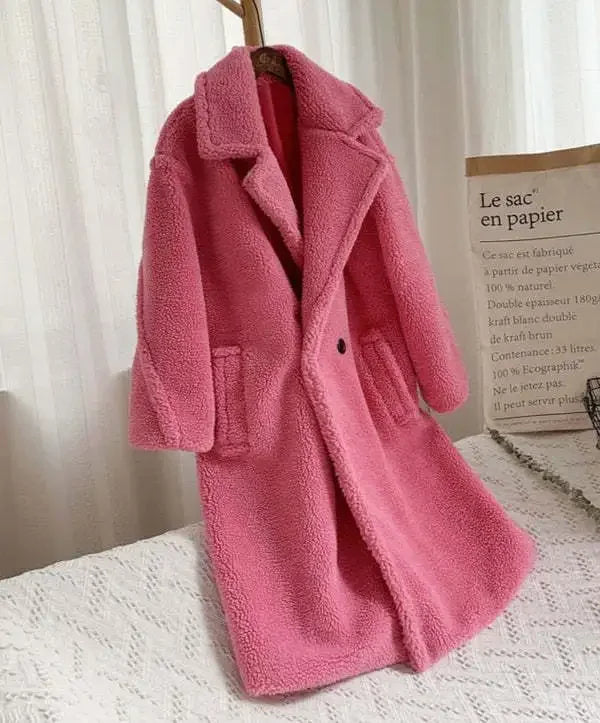 Pink teddy coat on a hanger against a white curtain background