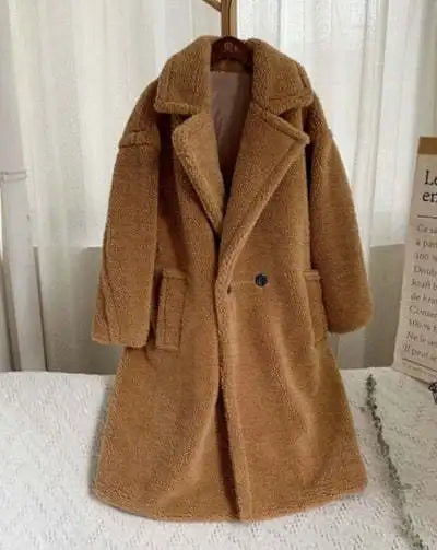 Brown teddy coat on a white surface with a blurred background