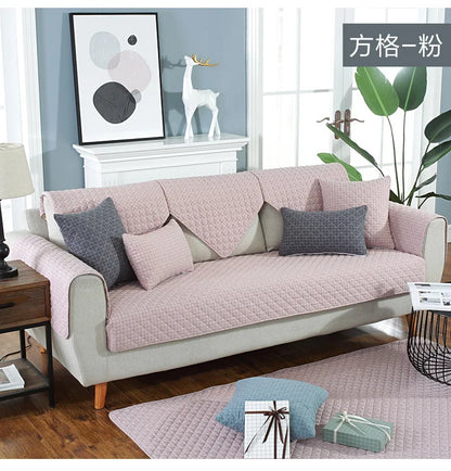 Living room with a pink sofa and decorative pillows, featuring a plant and framed art on a wall.