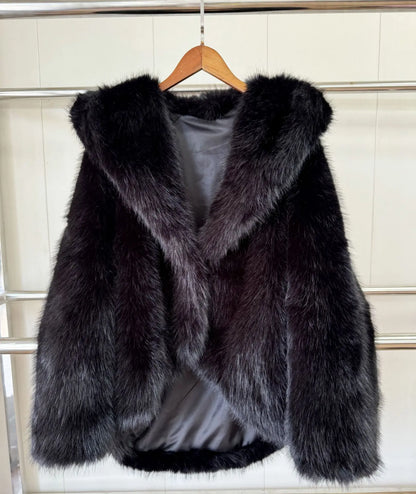 Black fur coat on a hanger against a white tiled wall.