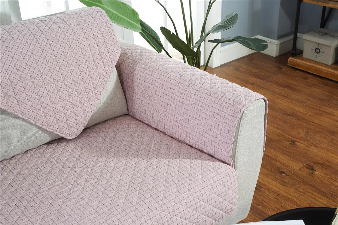 Pink textured sofa cover on a gray sofa with a plant and wooden floor in the background