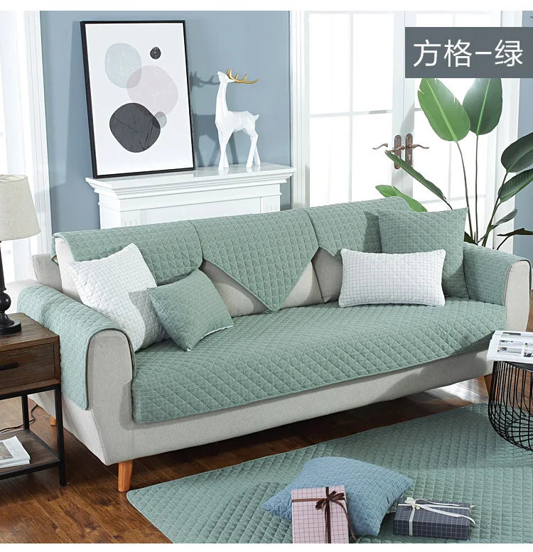 Green sofa cover on a sofa in a living room with decor elements.