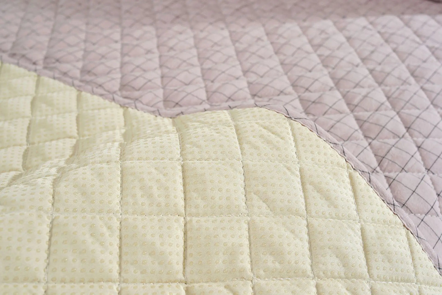 Close-up of a quilt with diamond pattern in light green and pink colors.