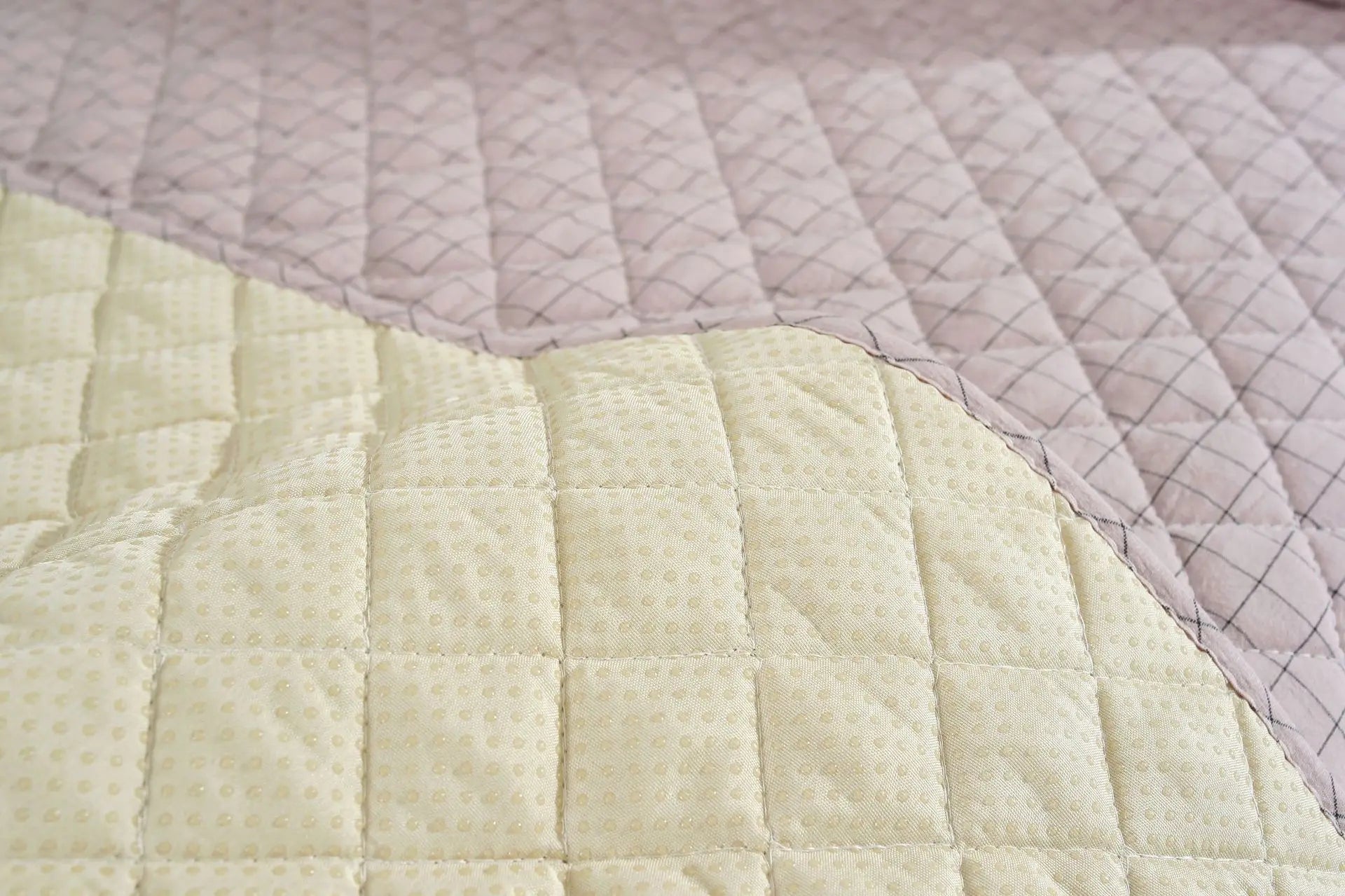 Close-up of a quilt with diamond pattern in light green and pink colors.