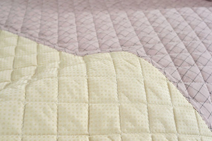 Close-up of a quilt with diamond pattern in light green and pink colors.